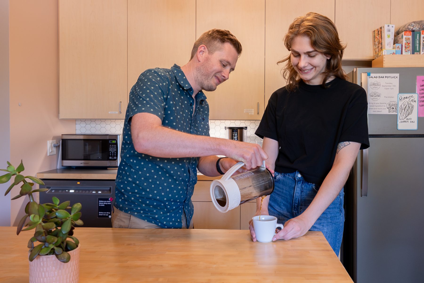 cohere-kitchen-coffee Two members pouring coffee in the Cohere kitchen