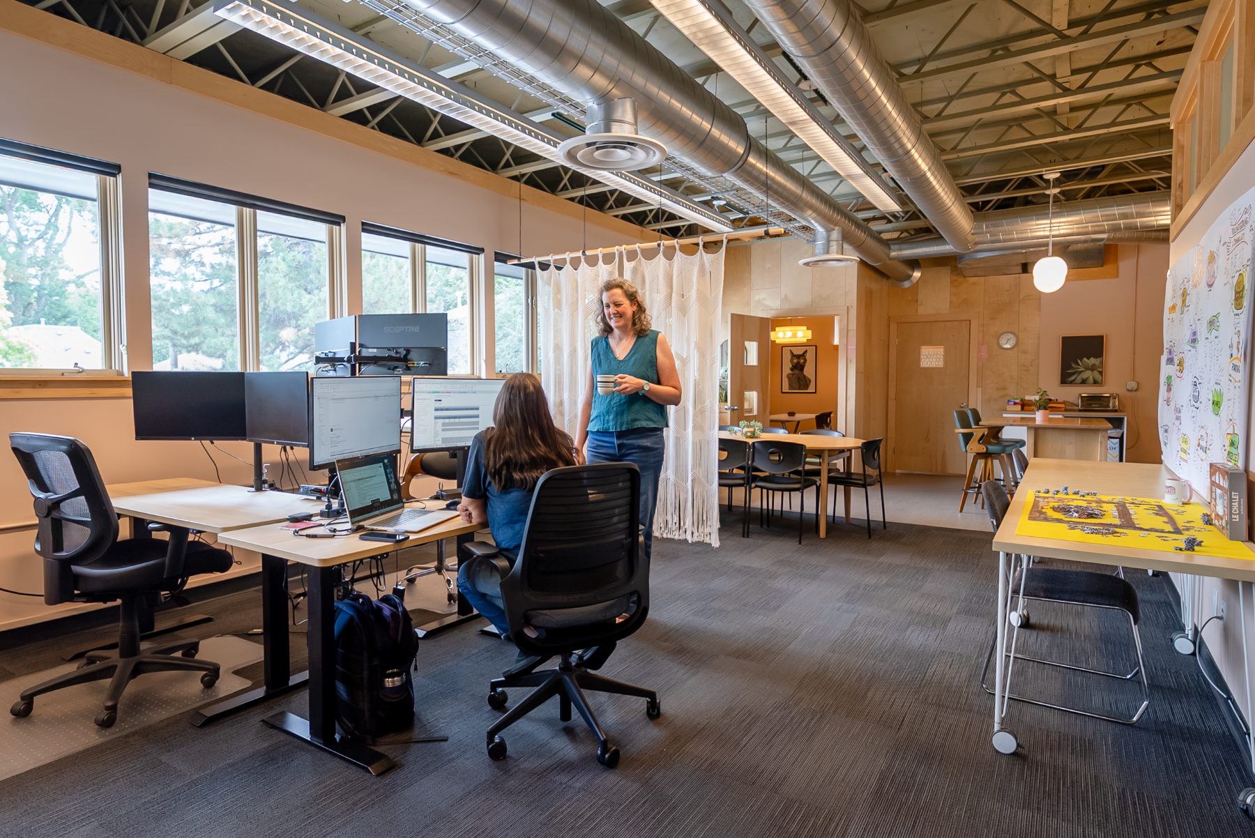 cohere-members-sit-stand-desks Members chatting over coffee at sit/stand desks